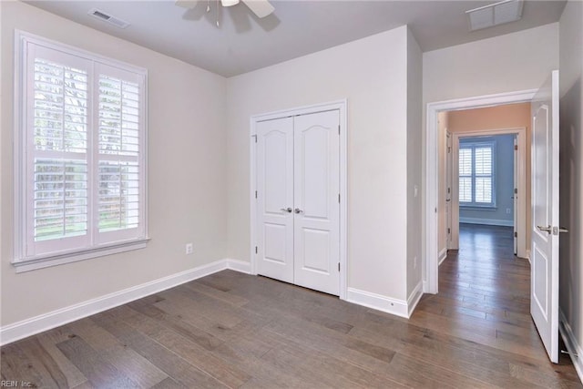 unfurnished bedroom featuring dark wood-style floors, baseboards, and visible vents