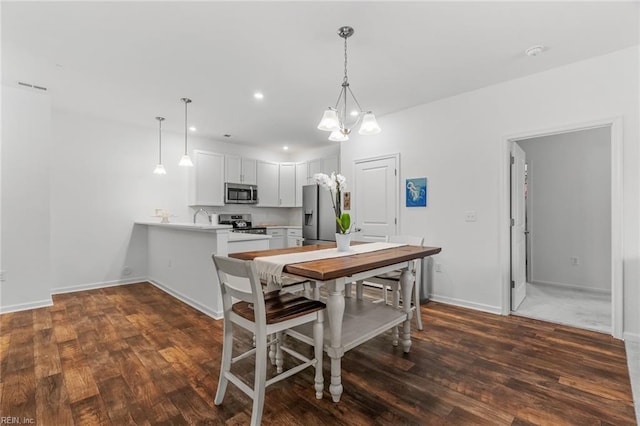 dining area featuring dark wood-type flooring, an inviting chandelier, baseboards, and recessed lighting