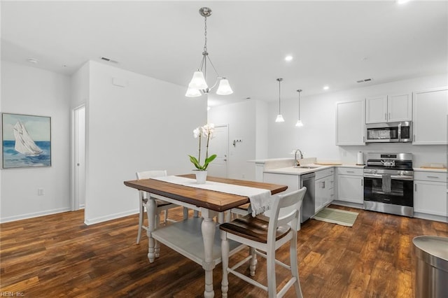 kitchen featuring a peninsula, visible vents, appliances with stainless steel finishes, and dark wood-style flooring