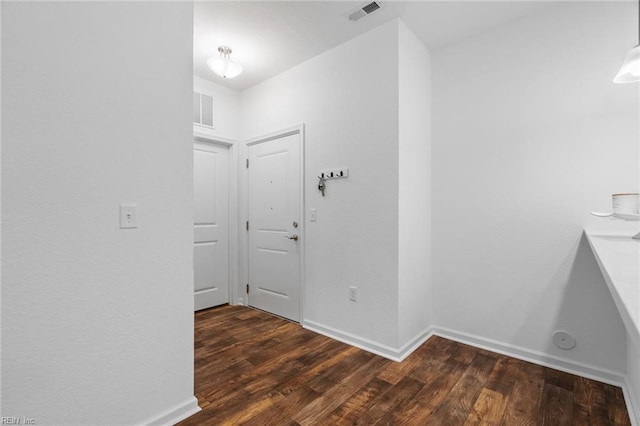 hallway featuring wood finished floors, visible vents, and baseboards