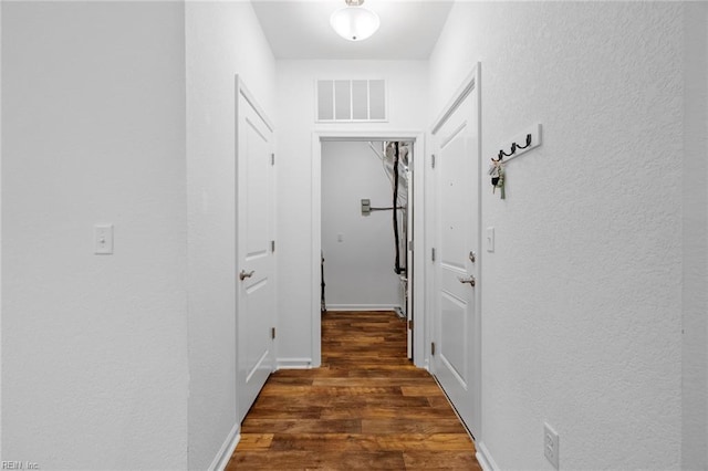 hall featuring a textured wall, visible vents, and wood finished floors