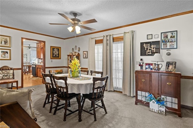 dining room featuring wainscoting, a textured ceiling, a ceiling fan, and crown molding