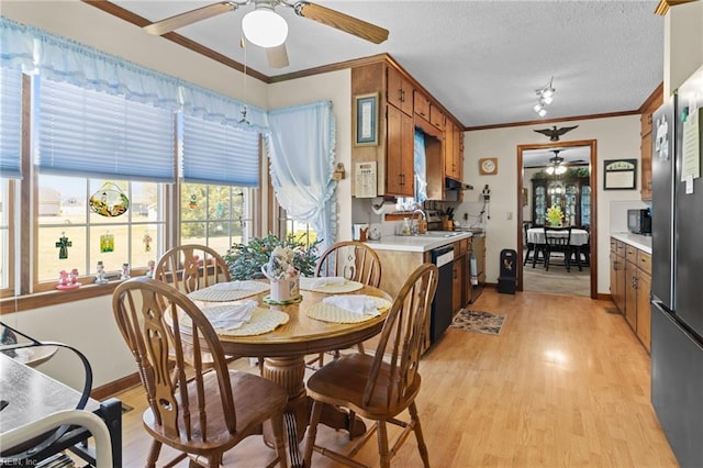 dining space with crown molding, light wood-style flooring, a ceiling fan, and baseboards