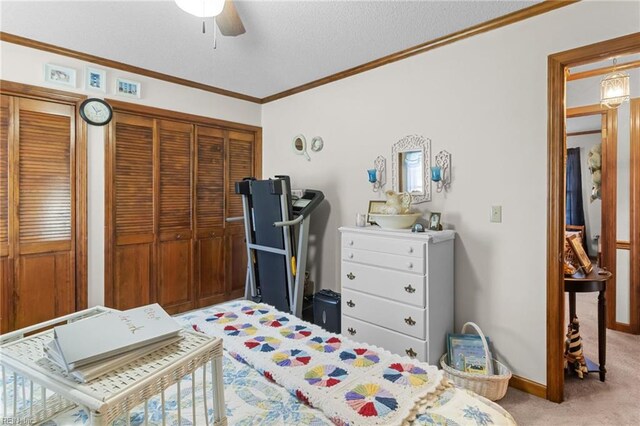 carpeted bedroom featuring crown molding, ceiling fan, a textured ceiling, and multiple closets
