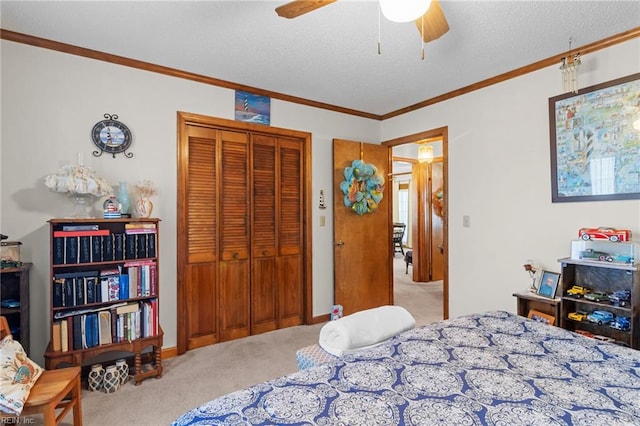 bedroom with ceiling fan, a textured ceiling, a closet, ornamental molding, and carpet floors