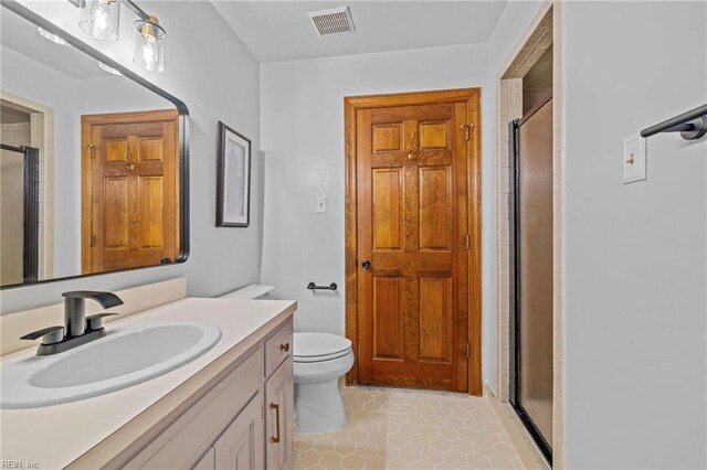 full bathroom with a shower stall, vanity, visible vents, and toilet