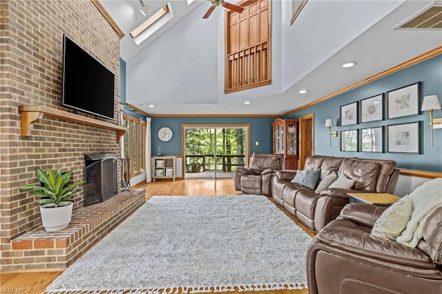 living area with a fireplace, crown molding, visible vents, ceiling fan, and wood finished floors