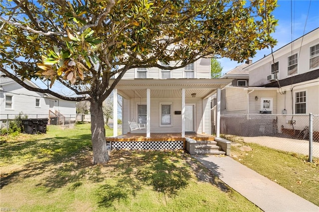 view of front facade featuring a front yard, fence, cooling unit, and covered porch