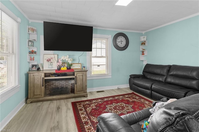 living area featuring light wood finished floors, baseboards, ornamental molding, and visible vents