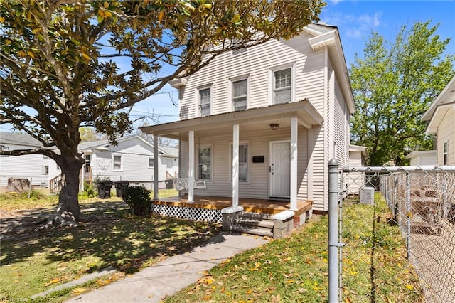 view of front of home with covered porch, fence, and a front lawn