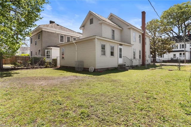 back of house with a yard, a fenced backyard, entry steps, and a chimney