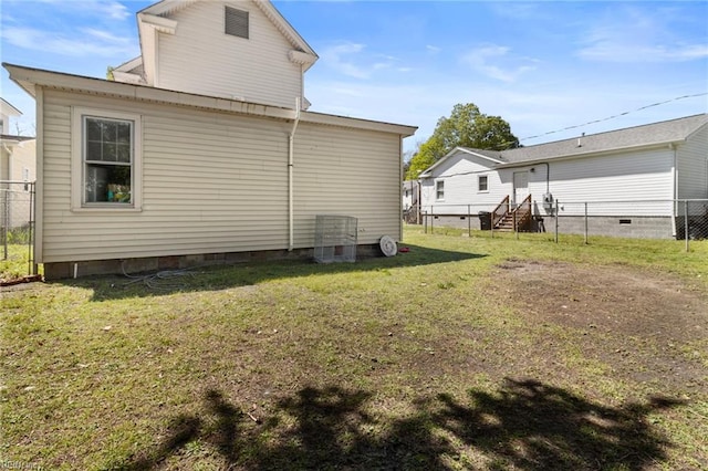 back of property featuring crawl space, a yard, and fence