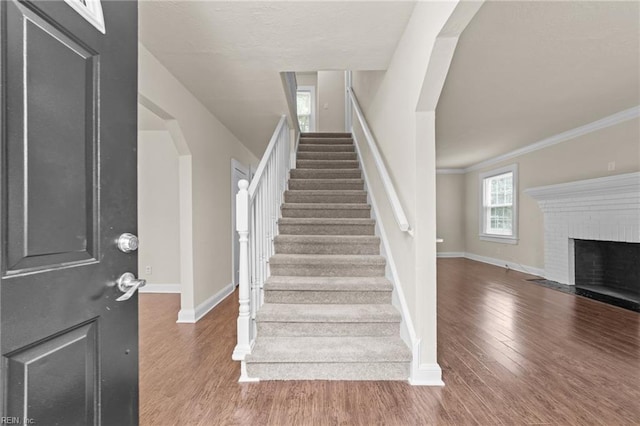 entrance foyer featuring baseboards, arched walkways, wood finished floors, and stairs