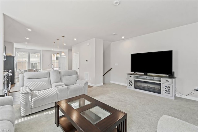 living area with recessed lighting, visible vents, light colored carpet, and baseboards