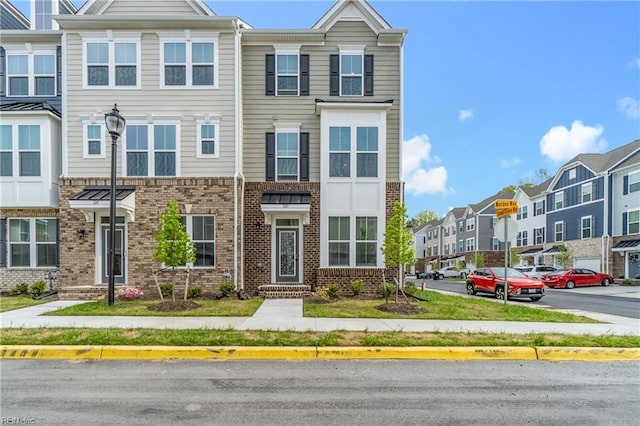 townhome / multi-family property with uncovered parking, a residential view, and brick siding