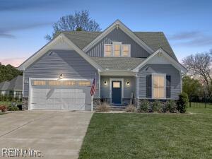 craftsman-style home featuring an attached garage, concrete driveway, and a front lawn