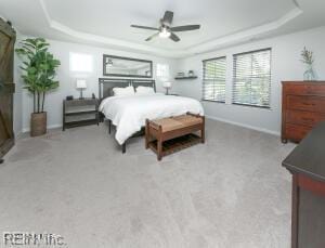 bedroom featuring a raised ceiling, ceiling fan, and baseboards