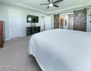 bedroom with baseboards, carpet flooring, a ceiling fan, a barn door, and a raised ceiling