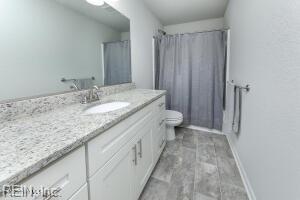 full bath with toilet, vanity, and a shower with shower curtain