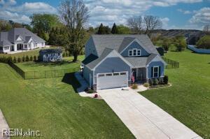 view of front of property featuring an attached garage, concrete driveway, and a front lawn