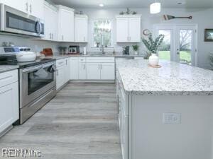 kitchen featuring white cabinets, light wood-type flooring, a center island, and stainless steel appliances