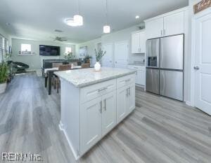 kitchen featuring white cabinets, light wood finished floors, a ceiling fan, and stainless steel fridge