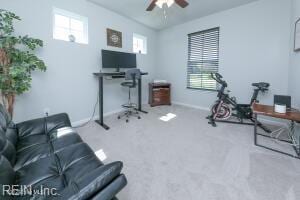 carpeted office space featuring baseboards and ceiling fan