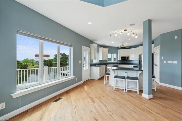 89 Sandy Bay Dr, Poquoson, VA 23662 - kitchen featuring a kitchen breakfast bar, dark countertops, stainless steel appliances, white cabinets, and visible vents