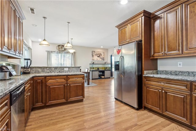 kitchen with decorative light fixtures, light wood finished floors, stainless steel appliances, and visible vents