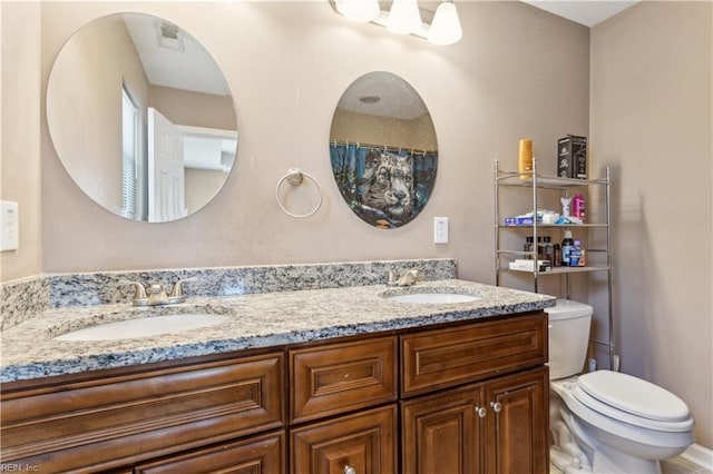 bathroom with double vanity, toilet, and a sink