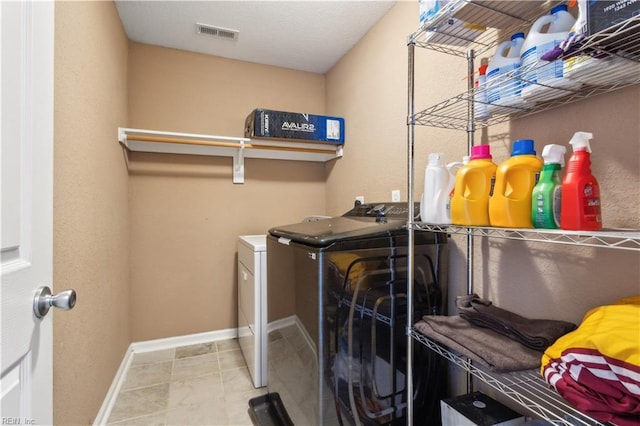 laundry room featuring tile patterned flooring, laundry area, visible vents, washing machine and clothes dryer, and baseboards