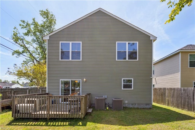 rear view of property featuring a wooden deck, central air condition unit, a lawn, and a fenced backyard