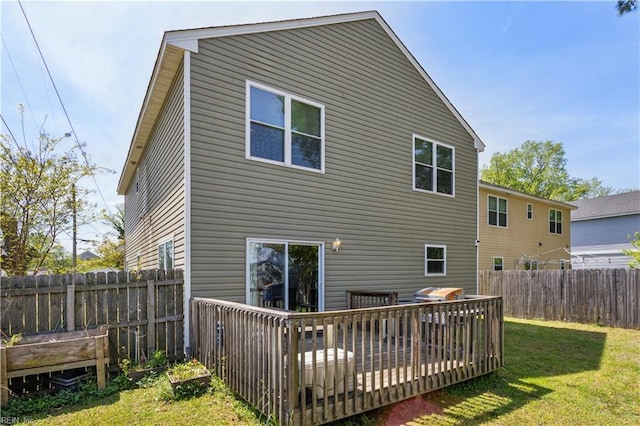 back of property with a lawn, a fenced backyard, and a deck