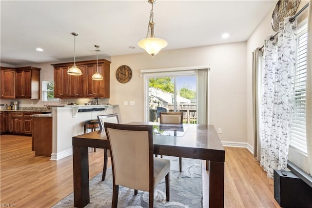 dining room with recessed lighting, baseboards, a wealth of natural light, and light wood-type flooring