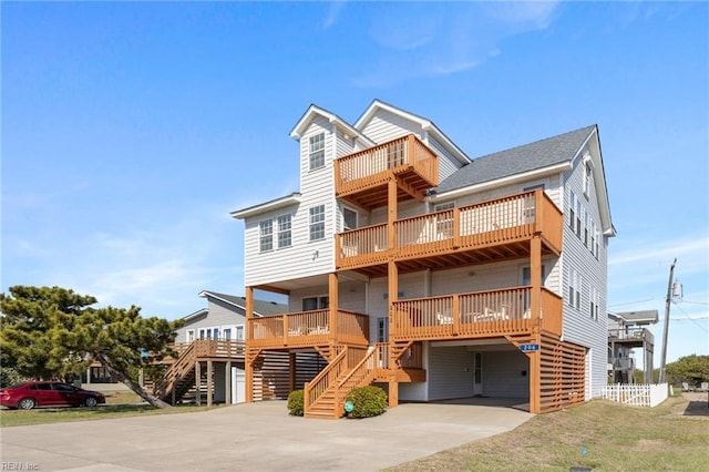 206 E Palmetto St, Kill Devil Hills, NC 27948 - raised beach house featuring a carport, concrete driveway, a front lawn, and stairway