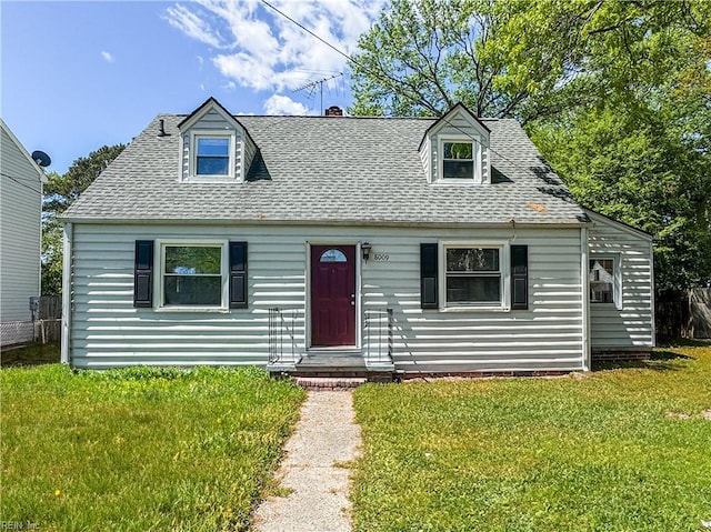 cape cod house with fence, roof with shingles, and a front yard