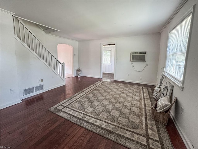 foyer with stairway, wood finished floors, arched walkways, visible vents, and a wall unit AC