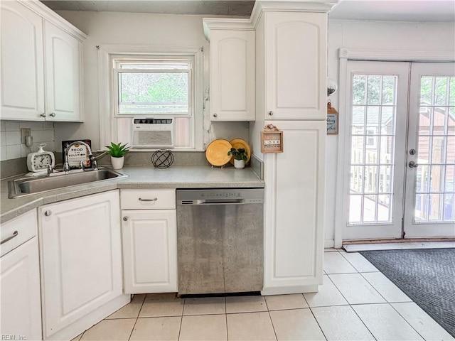 kitchen with light tile patterned floors, stainless steel dishwasher, a sink, and a wealth of natural light