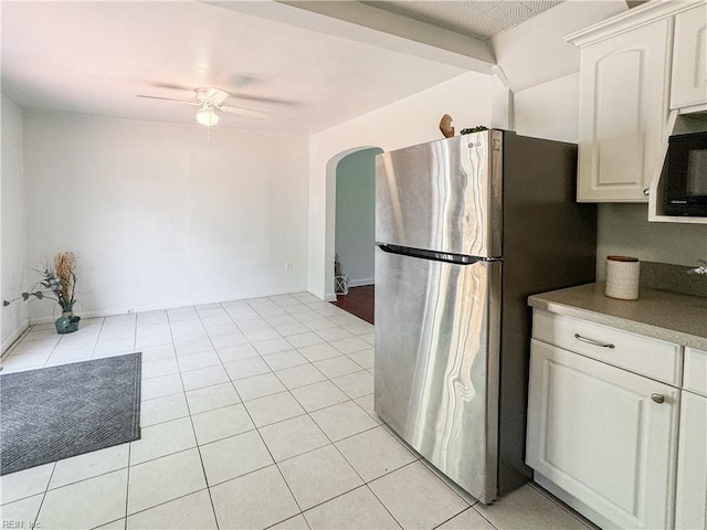 kitchen with arched walkways, freestanding refrigerator, white cabinetry, a ceiling fan, and black microwave