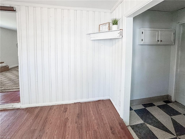 interior space featuring tile patterned floors, baseboards, and wood walls