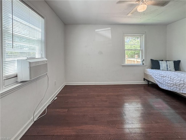 unfurnished bedroom with baseboards, a ceiling fan, dark wood-type flooring, and cooling unit