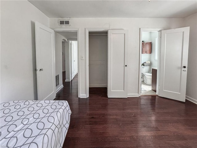 bedroom featuring a closet, dark wood finished floors, visible vents, and baseboards