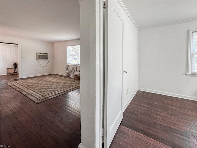 empty room with baseboards, crown molding, hardwood / wood-style flooring, and a wall mounted air conditioner
