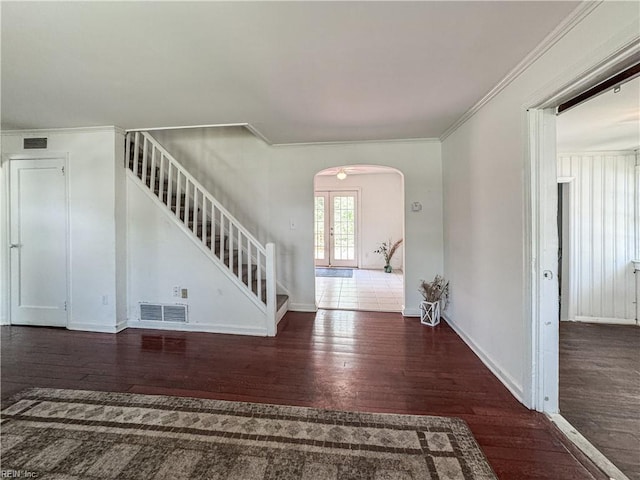 entryway with wood finished floors, stairs, arched walkways, ornamental molding, and visible vents