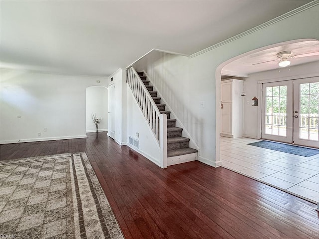 foyer entrance featuring arched walkways, stairs, a ceiling fan, and hardwood / wood-style flooring