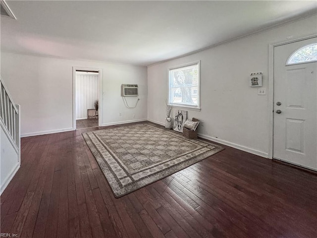 foyer with a wall mounted air conditioner, wood-type flooring, baseboards, and crown molding