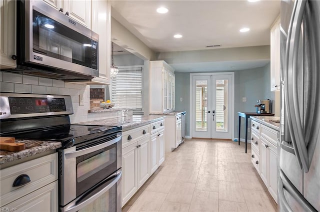 kitchen featuring decorative backsplash, a wealth of natural light, stainless steel appliances, and french doors