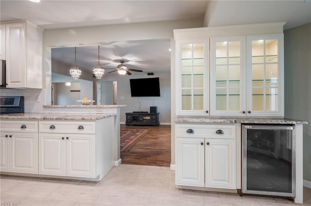 kitchen with white cabinets, wine cooler, decorative light fixtures, and light stone counters