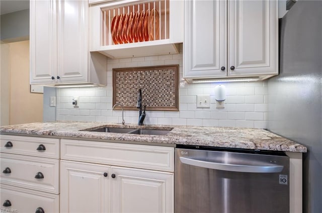 kitchen with backsplash, stainless steel dishwasher, white cabinetry, and a sink