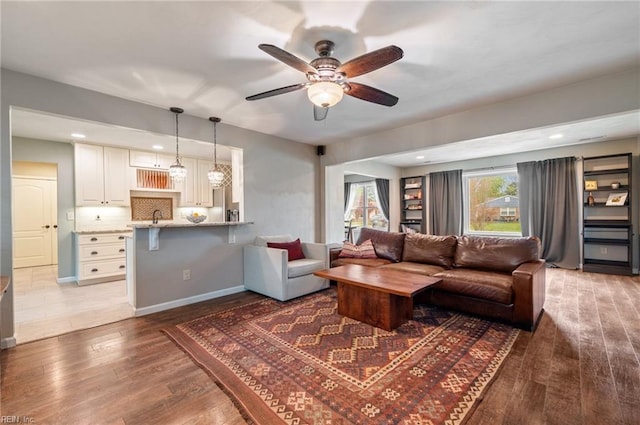 living area featuring baseboards, a ceiling fan, wood finished floors, and recessed lighting